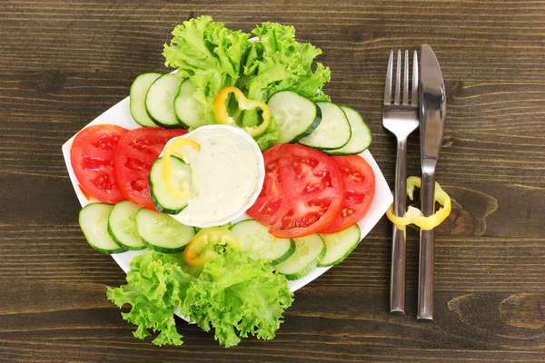 Нарезанные овощи и соус на тарелке на деревянном столе — стоковое фото
