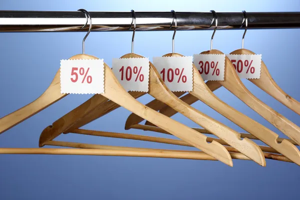 Cabides de roupas de madeira como símbolo de venda no fundo azul — Fotografia de Stock