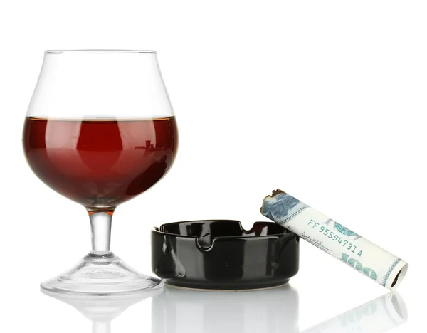 Cigar of the 100 dollar bill and an ashtray and glass of brandy isolated on white — Stock Photo, Image