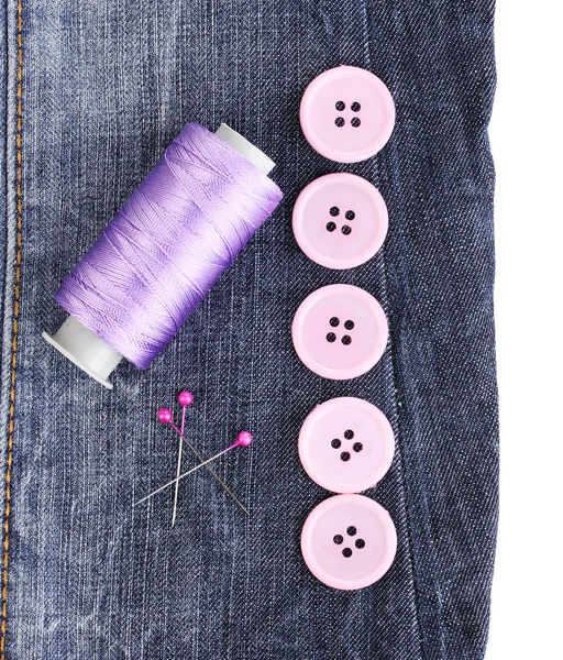 Colorful sewing buttons with thread on jeans isolated on white — Stock Photo, Image