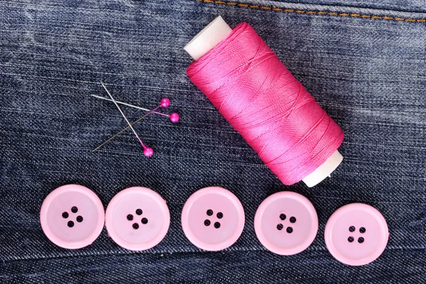 Boutons à coudre colorés avec fil sur jeans gros plan — Photo