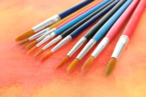 Brushes on bright abstract gouache painted background — Stock Photo, Image