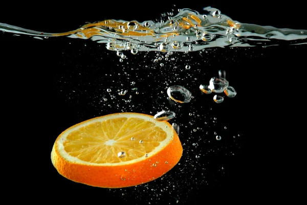 Orangenscheibe im Wasser auf schwarzem Hintergrund — Stockfoto