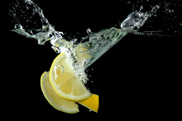 Diiris lemon di air pada latar belakang hitam — Stok Foto