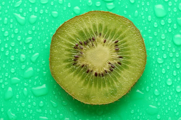 Skiva kiwi med droppe på grön bakgrund — Stockfoto
