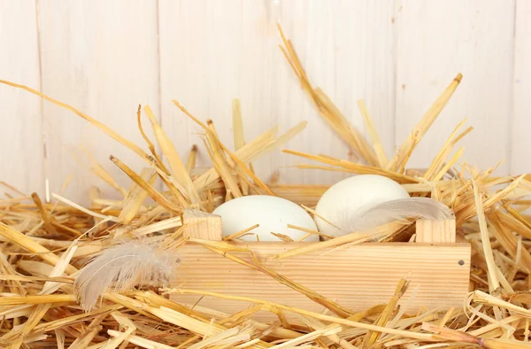 Белые яйца в деревянной коробке на соломе на белом деревянном фоне — стоковое фото