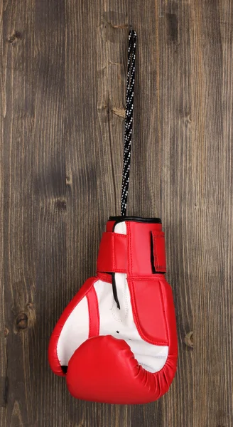 Gant de boxe rouge suspendu sur fond en bois — Photo