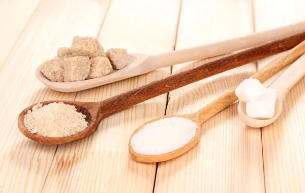Açúcar branco e mascavo em colheres no fundo de madeira — Fotografia de Stock