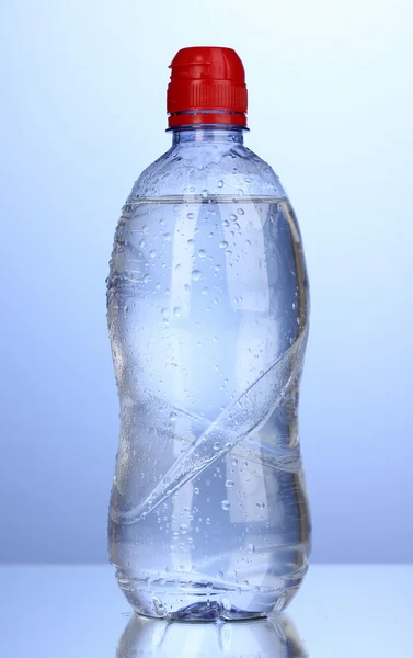 Plastikflasche mit Wasser auf blauem Hintergrund — Stockfoto