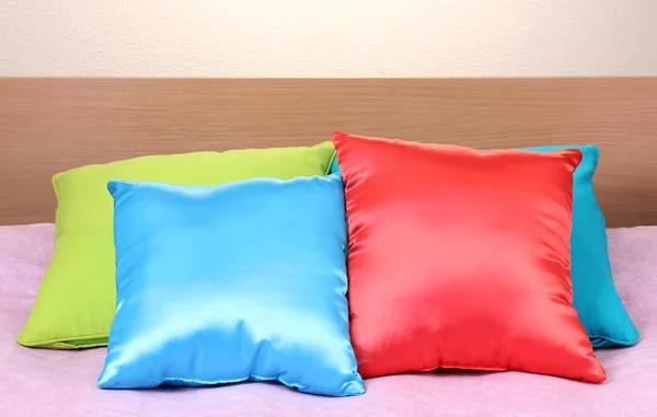 Яркие подушки на кровати на бежевом фоне — стоковое фото