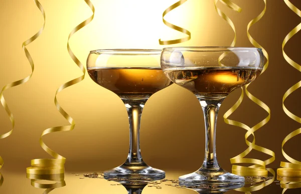 Glazen van champagne en streamer op gele achtergrond — Stockfoto
