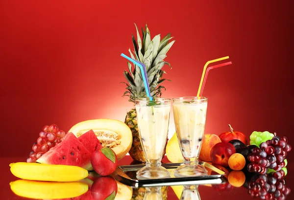 Melk schudt met fruit op rode achtergrond close-up — Stockfoto