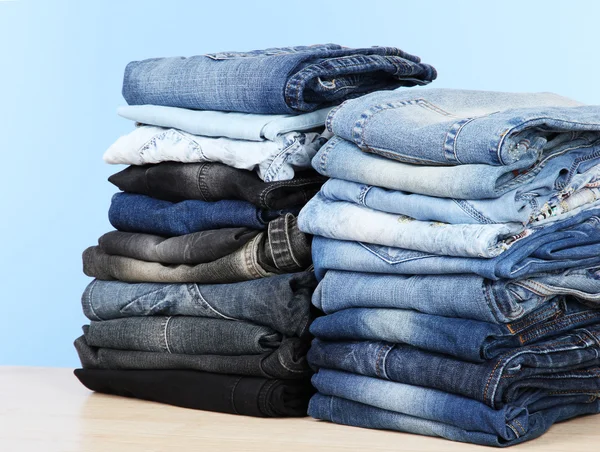 Beaucoup de jeans empilés dans un tas sur fond bleu — Photo