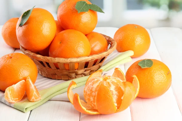 Tangerines with leaves in a beautiful basket, on white wooden table — Stock Photo, Image