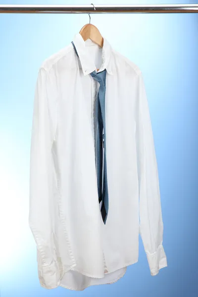 Camisa con corbata en percha de madera sobre fondo azul — Foto de Stock