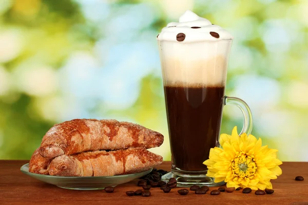 Taze kahve kokteyl cam ve parlak yeşil zemin üzerine simit ile fincan tabağı — Stok fotoğraf