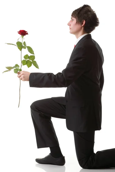 Νεαρός άνδρας παρουσιάζει ένα λουλούδι κόκκινο αυξήθηκε απομονωμένες — Φωτογραφία Αρχείου