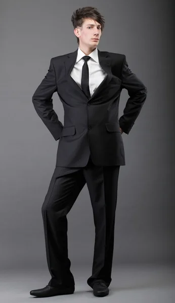 Młody biznesmen czarny komplet krawat dorywczo na szarym tle — Zdjęcie stockowe