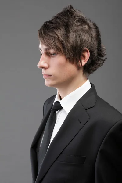 Giovane uomo d'affari vestito nero casual cravatta su sfondo grigio — Foto Stock