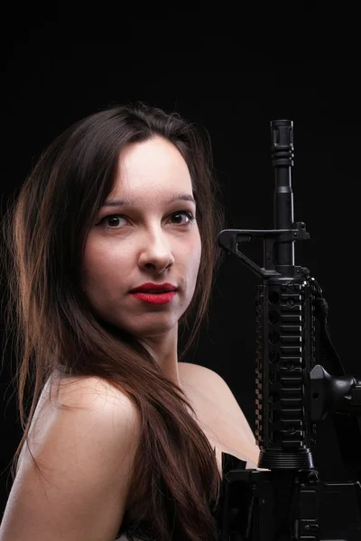 Menina segurando rifle no fundo preto — Fotografia de Stock