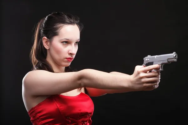 Сексуальная молодая женщина - пистолет на черном фоне — стоковое фото