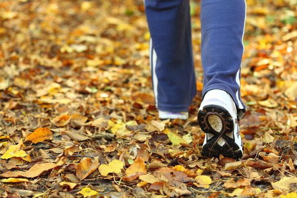 Woman walking cross country trail in autumn forest