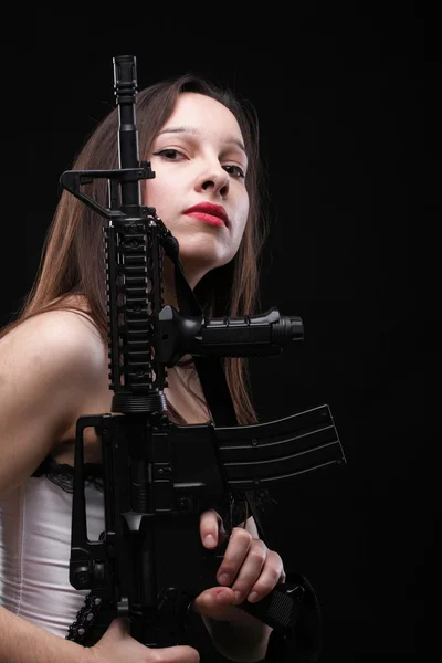 Menina segurando rifle no fundo preto — Fotografia de Stock