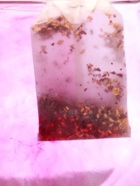 Красный чайный пакетик в горячей воде — стоковое фото