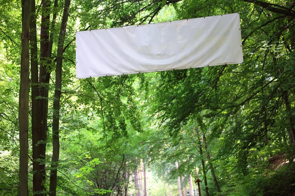 Placa branca em branco banner árvores verdes — Fotografia de Stock