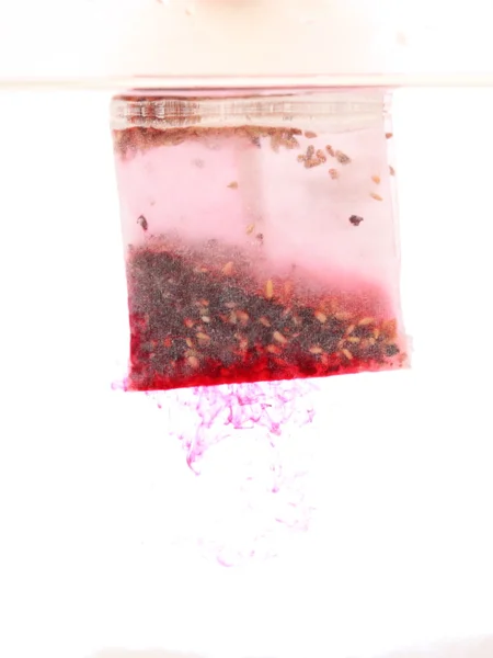 Красный чайный пакетик в горячей воде — стоковое фото