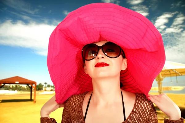 Menina na praia em um chapéu vermelho, um óculos grandes — Fotografia de Stock