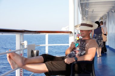 A man enjoying a cocktail on the liner clipart