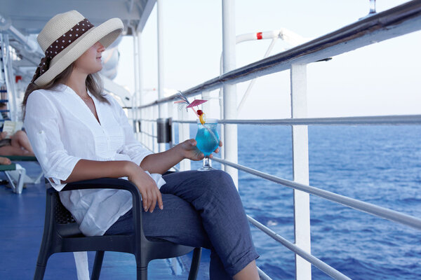 A woman in a hat and a cocktail on the liner