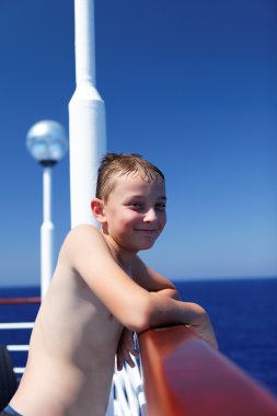 Smiling boy cruises the ocean on a ship clipart