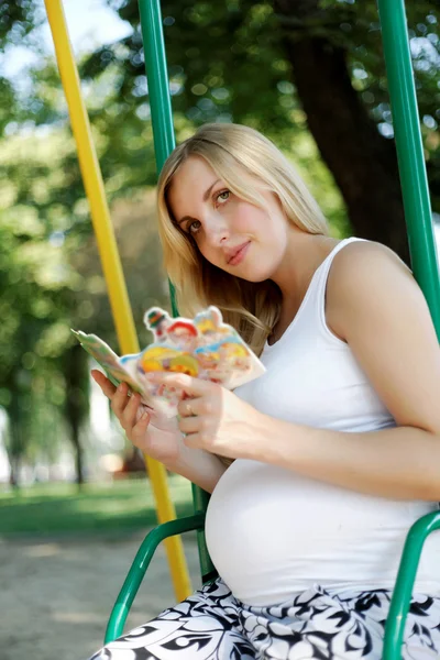 Беременная девушка в парке с книгой — стоковое фото