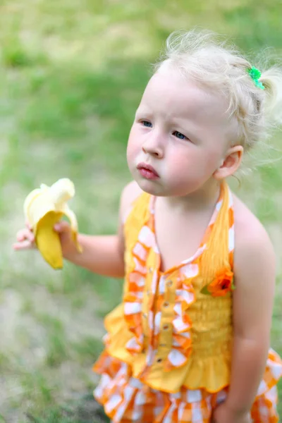 Verärgert isst das Mädchen eine Banane — Stockfoto