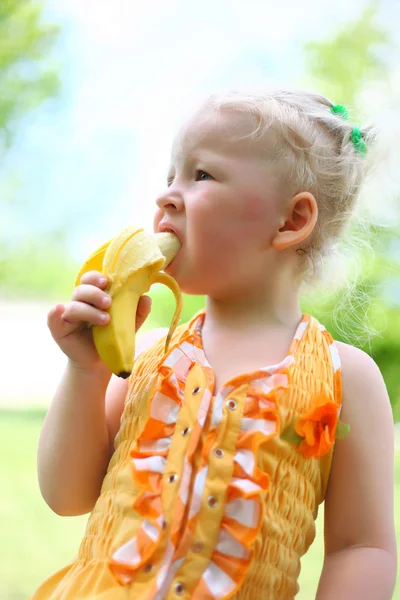 かわいい女の子の肖像画はバナナを食べる — ストック写真