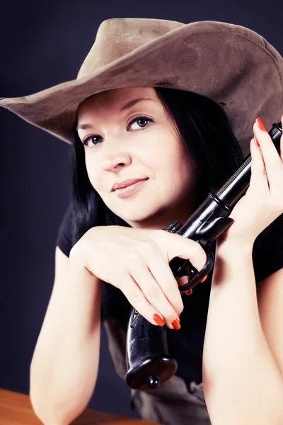 Mooi meisje in een hoed met een pistool — Stockfoto