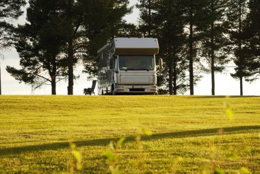 Mobile home on camping site into the sunset. clipart