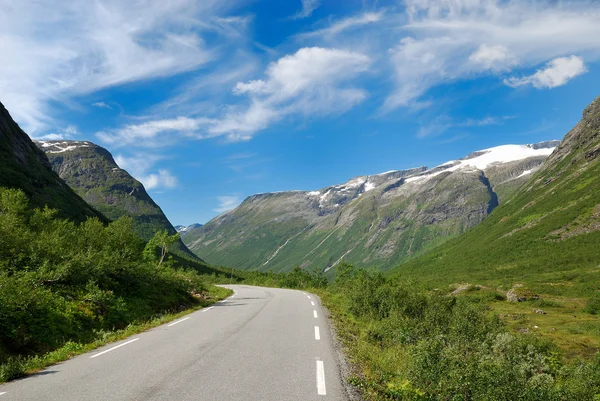 Narrow road running past green mountains. — Stock Photo, Image