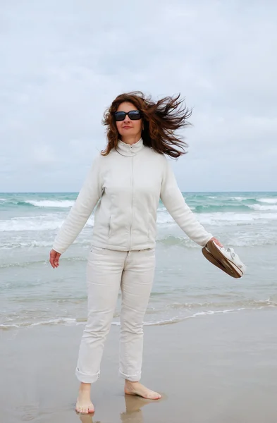Mujer descalza en la playa contra el mar y el cielo nublado . —  Fotos de Stock