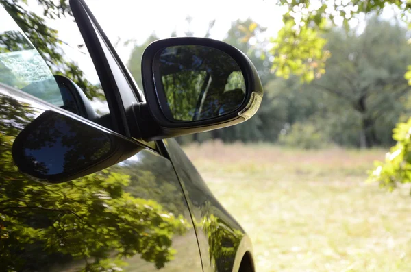 Car with reflections of green trees in sunny lawn. — Stock Photo, Image