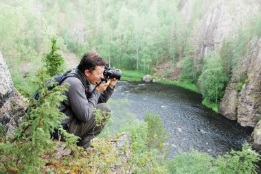 Man photographing on the top of taiga forest. clipart