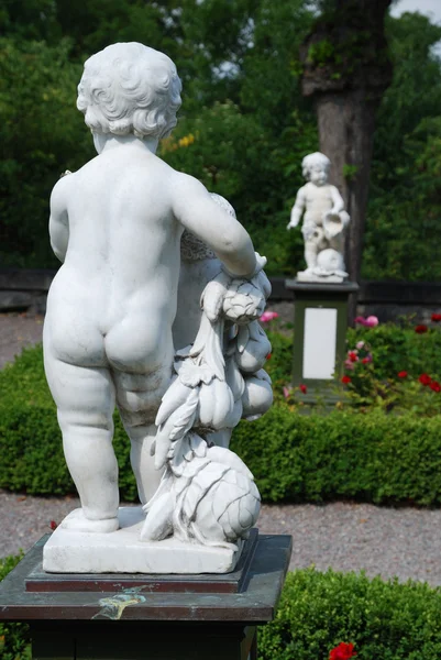 Белые мраморные статуи Купидона в розарии — стоковое фото