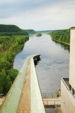 Rapid river with hydro power plant in taiga forest. clipart