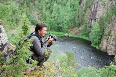 Happy man with camera on the top of taiga forest. clipart