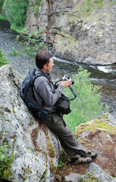 Man with camera on the rock over mountain river. — Stock Photo, Image