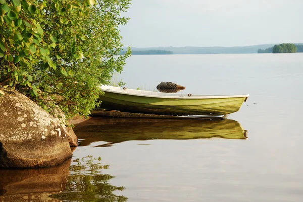 Финское озеро с золотой лодкой на закате — стоковое фото