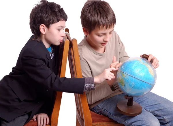 Двоє хлопчиків, які досліджують глобус ізольовані на білому — стокове фото