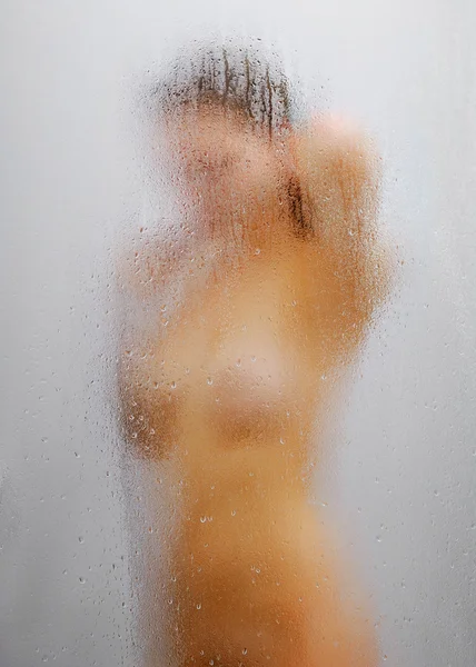 Женщина в душе через плачущее стекло — стоковое фото